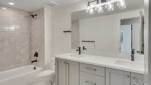 Full bathroom featuring vanity, tiled shower / bath combo, and toilet