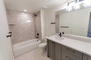 Full bathroom featuring vanity, tiled shower / bath combo, and toilet