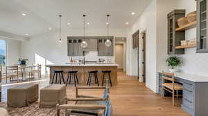 Kitchen featuring gray cabinetry, light hardwood / wood-style floors, a kitchen bar, and hanging light fixtures