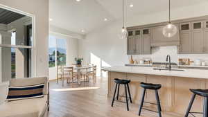 Kitchen featuring pendant lighting, light hardwood / wood-style floors, a kitchen breakfast bar, and lofted ceiling