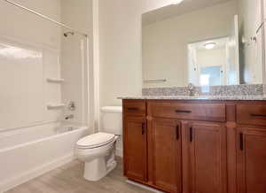 Full bathroom with toilet, vanity, wood-type flooring, and tub / shower combination