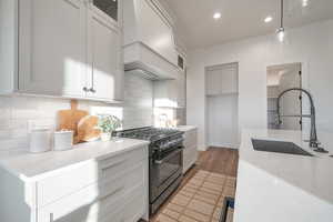 Kitchen featuring tasteful backsplash, sink, decorative light fixtures, and high end stainless steel range oven