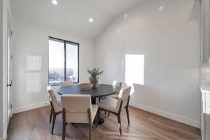 Dining space with light wood-type flooring and vaulted ceiling