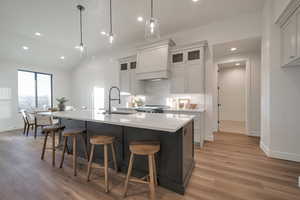 Kitchen featuring hanging light fixtures, light wood-type flooring, sink, and a large island with sink