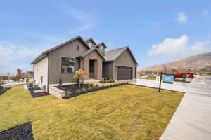 View of front of house with a mountain view, a garage, central air condition unit, and a front lawn