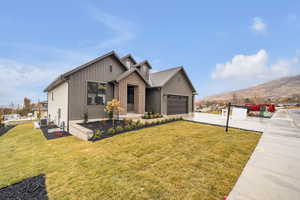 View of front of home featuring a mountain view, central AC unit, a garage, and a front lawn