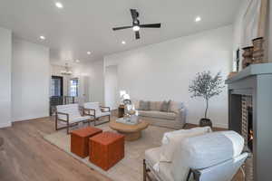 Living room featuring ceiling fan with notable chandelier and light hardwood / wood-style floors