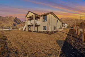 Back house at dusk featuring a mountain view and a balcony