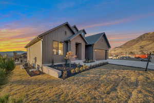 View of front of home featuring a lawn, a mountain view, a garage, and central AC