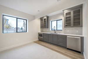 Kitchen featuring appliances with stainless steel finishes, light wood-type flooring, gray cabinets, and sink