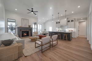 Living room featuring ceiling fan, light hardwood / wood-style flooring, sink, and a brick fireplace