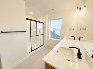 Bathroom with vanity, wood-type flooring, double sink, and walk in shower