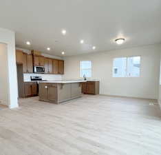 Kitchen featuring a healthy amount of sunlight, a kitchen island with sink, stainless steel appliances, and a kitchen breakfast bar