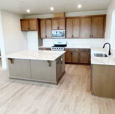 Kitchen with sink, a kitchen breakfast bar, light hardwood / wood-style flooring, stove, and a kitchen island