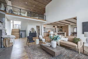 Living room featuring light wood-type flooring, a towering ceiling, sink, beam ceiling, and a fireplace