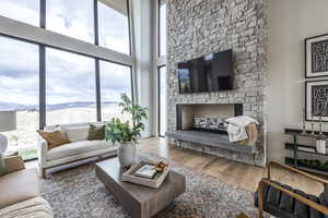 Living room featuring hardwood / wood-style flooring, a mountain view, a stone fireplace, and a towering ceiling