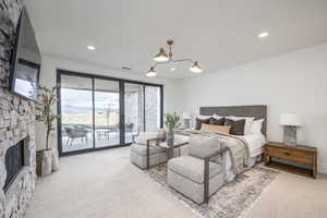 Bedroom with access to exterior, light carpet, a chandelier, and a stone fireplace