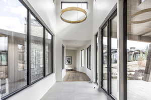 Hallway featuring a towering ceiling, light hardwood / wood-style flooring, and a healthy amount of sunlight