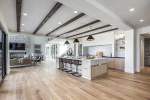 Kitchen with pendant lighting, a spacious island, light hardwood / wood-style flooring, light brown cabinetry, and beamed ceiling