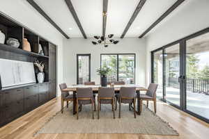 Dining area with beamed ceiling, light hardwood / wood-style floors, and a notable chandelier