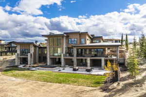 Back of house with an outdoor living space with a fireplace, a patio area, and a yard