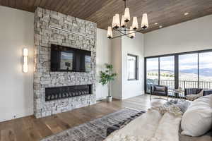 Living room with wood-type flooring, wood ceiling, a fireplace, and an inviting chandelier