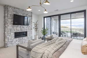 Bedroom featuring a stone fireplace, a mountain view, carpet floors, and access to exterior