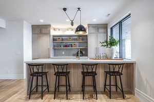 Kitchen with light hardwood / wood-style floors, a kitchen bar, kitchen peninsula, and sink