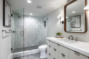 Bathroom with tile patterned floors, vanity, toilet, and a shower with door