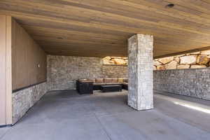 Interior space with concrete floors, wood ceiling, wooden walls, and ornate columns