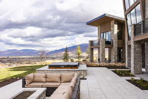 View of patio with a mountain view, an outdoor hangout area, a balcony, a covered hot tub, and a grill