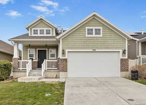 Craftsman house with a porch, a garage, and a front yard