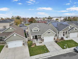 View of front of home with covered porch, solar panels, a garage, and a front lawn