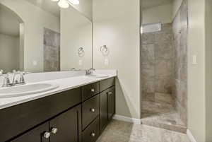 Bathroom featuring a tile shower and vanity