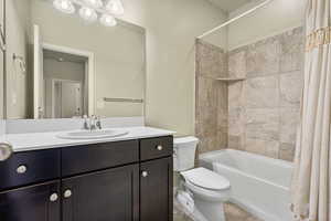 Full bathroom with vanity, shower / bath combo with shower curtain, tile patterned flooring, and toilet