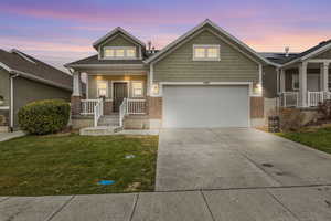 Craftsman house with a lawn, a porch, and a garage