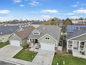 View of front of home with covered porch, a front yard, and solar panels