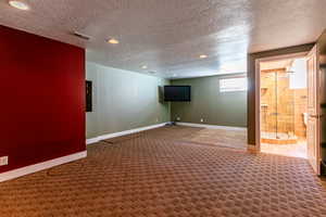 Basement family room with roughed in bar area, carpet and a textured ceiling