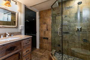 basement Bathroom with a shower with door, vanity, and a textured ceiling