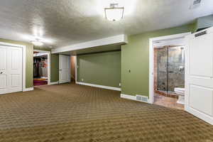 Basement bedroom with carpet and a textured ceiling