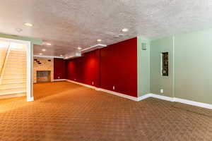 Basement family room with a fireplace, a textured ceiling, and carpet floors