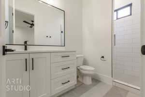 Bathroom with a tile shower, vanity, and toilet