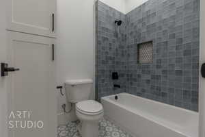 Bathroom featuring tile patterned floors, tiled shower / bath combo, and toilet