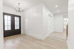 Foyer featuring light hardwood / wood-style flooring, french doors, and a notable chandelier