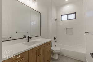 Full bathroom featuring toilet, vanity, tile patterned floors, and tiled shower / bath