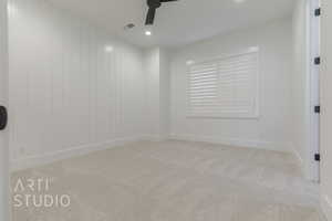 Spare room featuring ceiling fan, light colored carpet, and wood walls