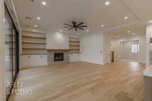 Unfurnished living room with ceiling fan, a fireplace, and light hardwood / wood-style floors