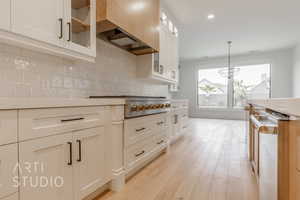 Kitchen featuring pendant lighting, dishwasher, backsplash, light wood-type flooring, and stainless steel gas cooktop