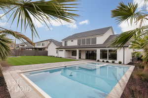 Back of property featuring a yard, a fenced in pool, and a patio