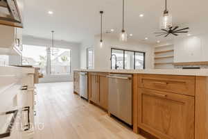 Kitchen featuring white cabinetry, light hardwood / wood-style flooring, ventilation hood, decorative light fixtures, and ceiling fan with notable chandelier